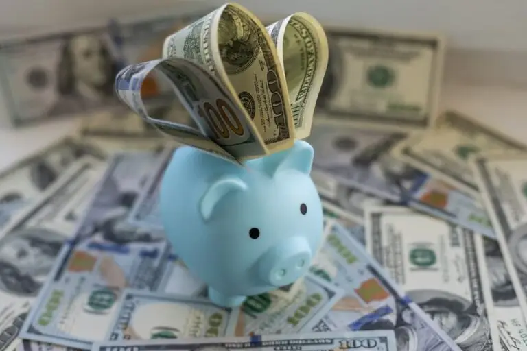 light-blue-piggy-bank-with-hundred-dollar-bills-on-scattered-us-currency-background